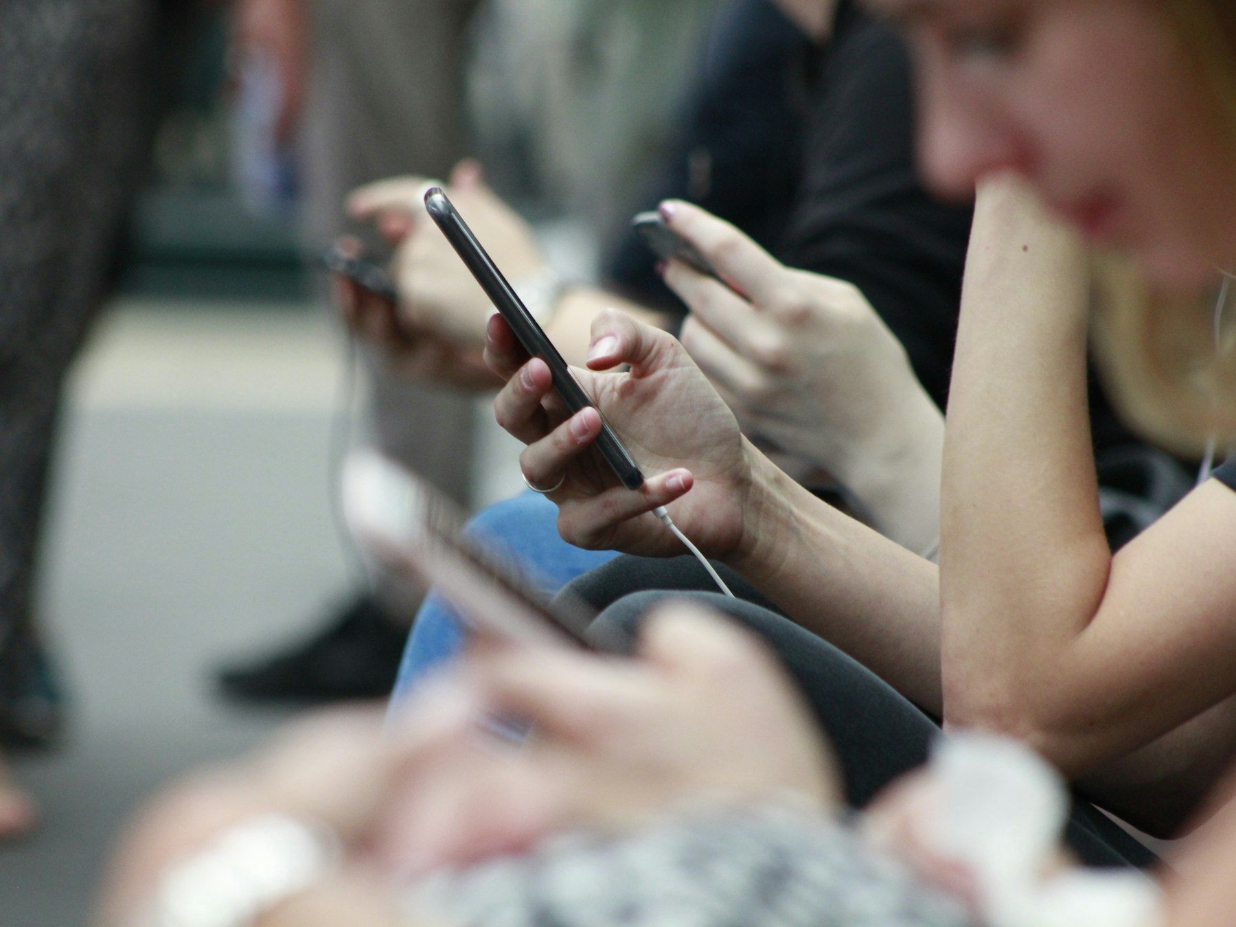 People sitting in a row, each reading their smartphone